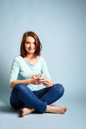 smiling woman hold gray gift box on blue backgroundの写真素材