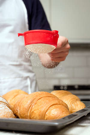baker sprinkled powdered sugar on top of the croissantの写真素材