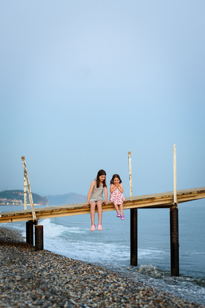 two girls are sitting on the pier at sea vacation.の写真素材
