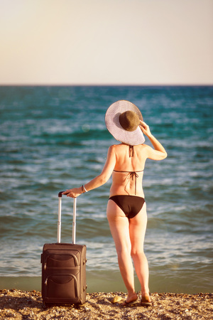 woman in swimsuit with suitcase on beachの写真素材