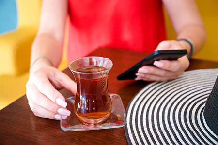 women in red dress and hand with turkish tea on the wooden table and hat .の写真素材