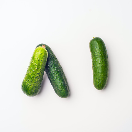 Green vegetables flat lay concept. Cucumber on white background, top view with empty space for text.の写真素材