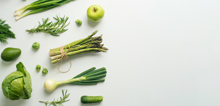 Green vegetables wide flat lay concept. Microgreens, brussels sprouts, asparagus, rosemary, avocado, onion, cabbage and cucumber on white background, top viewの写真素材