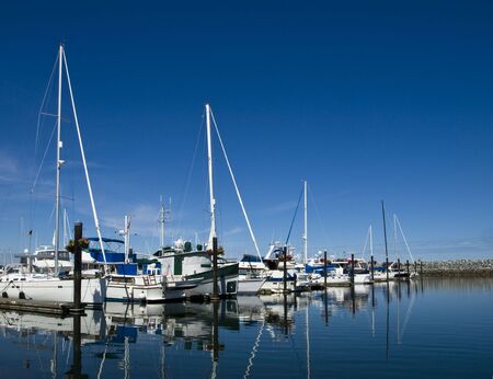 Sailboats in their stalls at marina behind the breakwater の写真素材