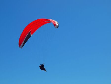 paraglider in the sky with red parachuteの写真素材