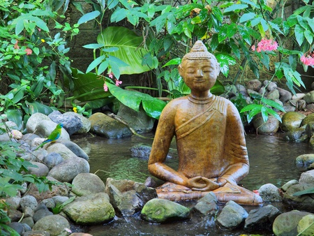 Buddha statue sitting on top of waterfallの写真素材