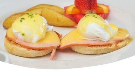 Breakfast plate with eggs Benedict, fries and fruitの写真素材