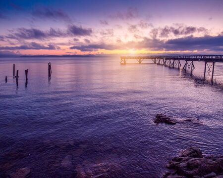 Wooden pier extending toward the setting sunの写真素材
