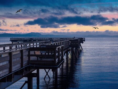 Wooden fishing pier extending from the shore into the oceanの写真素材