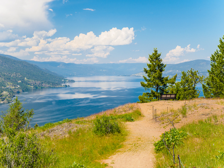 Mountain hiking trail with bench overlooking the lakeの写真素材