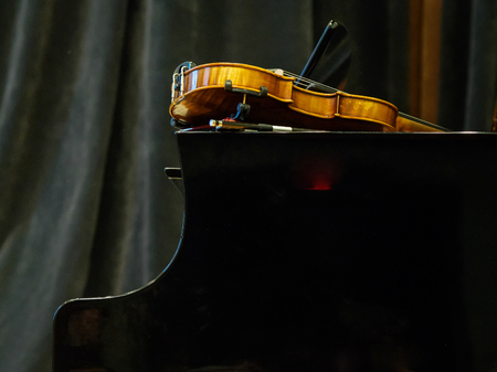 Violin on the grand piano in a concert hall, close-up