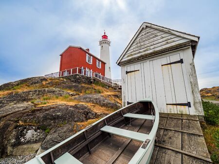 Old lighthouse with decrepit shed and old boatの写真素材