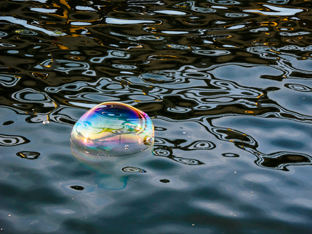Bright large soap bubbles on the water surfaceの写真素材