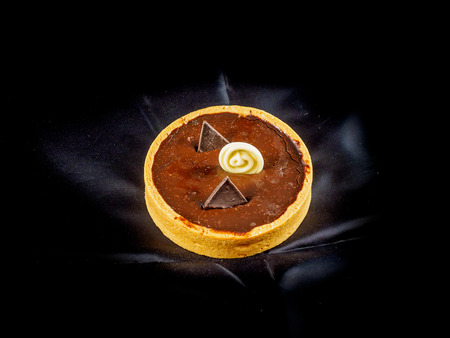Dessert of freshly baked tarts with chocolate filling on black backgroundの写真素材