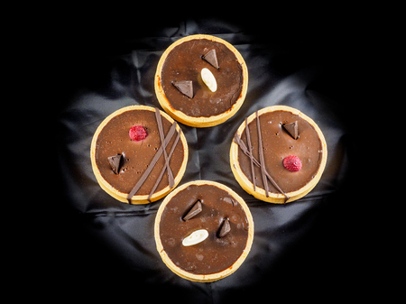 Dessert of freshly baked tarts with chocolate filling on black backgroundの写真素材