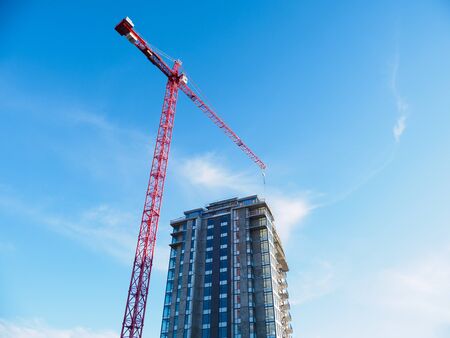 Construction crane on a building site against blue sky background