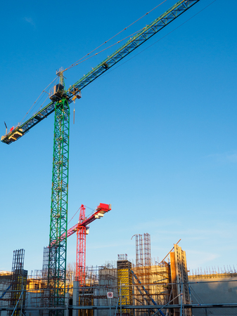 Construction crane on a building site against blue sky backgroundの写真素材