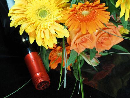Bouquet of flowers and bottle of wine arranged on black surfaceの写真素材