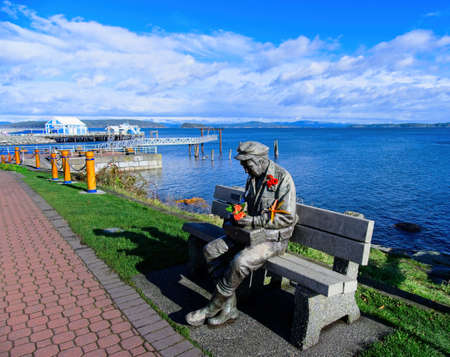 Sidney, BC Canada - November 13, 2020. Sculpture Old Man by the Sea at the fishing pier in Sidney, decorated with red poppies for Remembrance Day celebrationのeditorial素材
