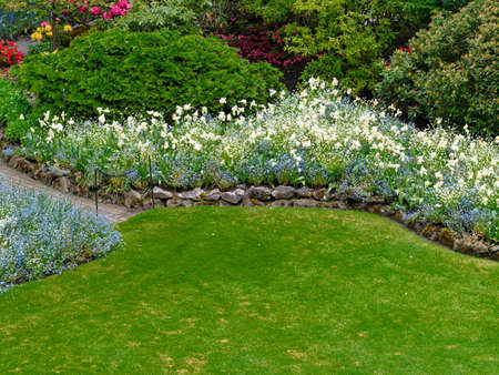 Springtime garden with walkways and flower beds covered with blooming flowersの写真素材