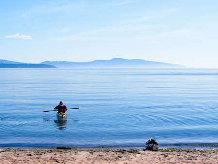 Man in a kayak leaving the ocean shoreの写真素材