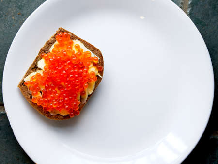 Red salmon caviar on the toast with butter on a white plateの写真素材