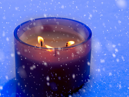 Candle burns in the snow during blizzard in Christmas timeの写真素材
