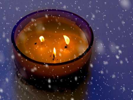 Candle burns in the snow during blizzard in Christmas timeの写真素材