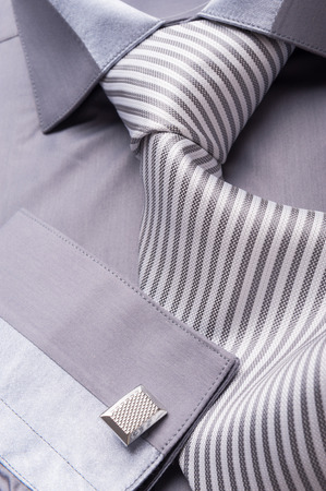 Close up photo of a folded grey shirt with a striped tieの写真素材