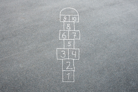 Hopscotch game being drawn with a chalk on the asphalt ground as seen from aboveの写真素材