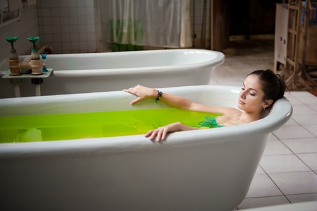 Wellness - young woman floating in Spa filled with water with pine tree and other herbs extractsの写真素材