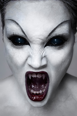Close up portrait of a screaming undead girl with sharp teeth, white skin and black eyesの写真素材