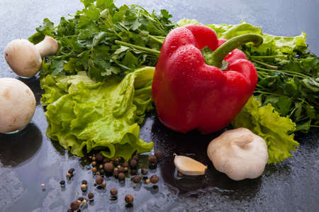 Red pepper, garlic, mushrooms, lettuce and parsley on a a glass with dropletsの写真素材