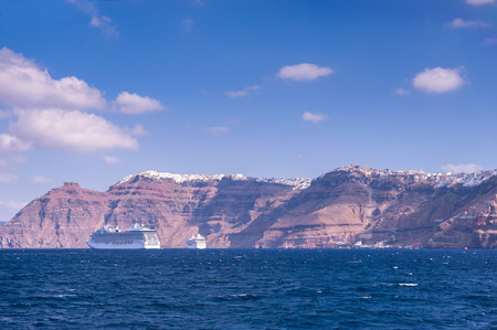 View on Santorini island with its typical high cliffs coastline and clear blue water shot on a sunny day. You can also see Oia and Fira cities in the backgroundの写真素材
