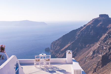 Mountain view from Oia, Santorini, with tables on a terrace on a sunny dayの写真素材
