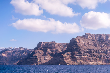 View on Santorini island with its typical high cliffs coastline and clear blue water shot on a sunny day. You can also see Oia and Fira cities in the backgroundの写真素材