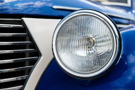 Closeup shot of a head lamps of a blue and white czech retro carの写真素材