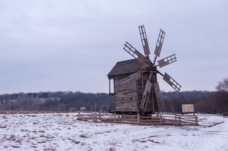 Landscape photo of an old wooden windmill on a winter cloudy dayの写真素材