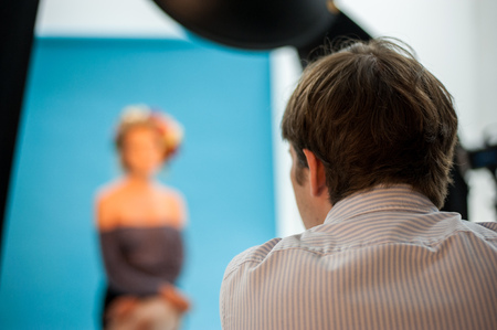 Backstage shot of a professional photoshoot in a studio with a model, photographer and light equipment.の写真素材
