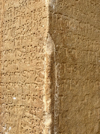 Inscriptions on the ancient temple stone walls. Ancient stone carving. Old stone wall texture. Tamil inscriptions in historical temple walls. Inscriptions in historical Kanchi Kailsanathar temple.の写真素材