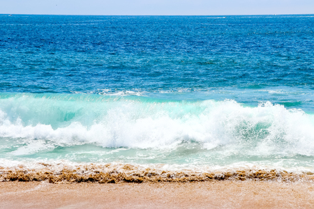 This is the beautiful waves at the beach with blue,white water  and brown sand. Use for background.の写真素材