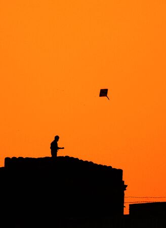 Man flying kite from his building topの写真素材