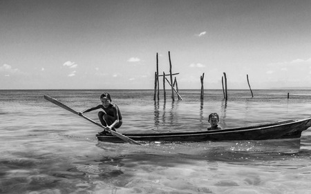 Bajau tribe kids having fun by rowing small boat near their village houses in Sea, Sabah Semporna, Malaysiaのeditorial素材