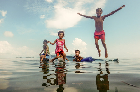 Bajau tribal kids having fun by jumping into sea from their boat, Sabah Semporna, Malaysia