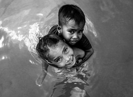 Bajau tribe girl carrying her little brother on her shoulder and playing in water, Semporna,...
