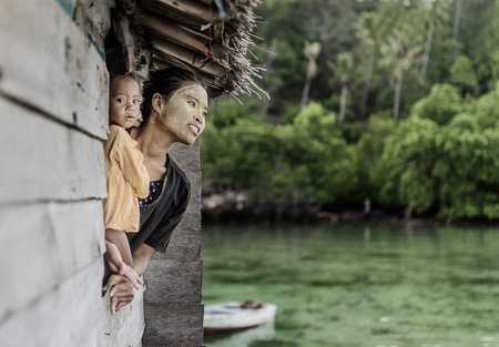 Mother and child looking outside window in Semporna sea village, Sabah Semporna, Malaysiaのeditorial素材