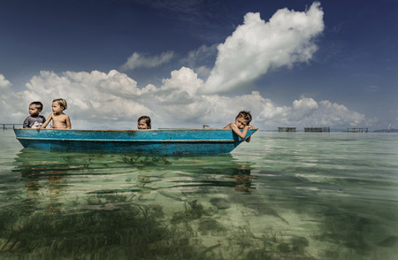 Bajau tribe kids having fun by rowing small boat near their village houses in Sea, Sabah Semporna, Malaysiaのeditorial素材