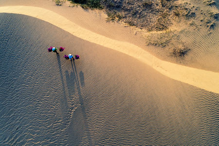 Woman carrying flower basket at sunset in Mui Ne sand dune, Vietnamの写真素材