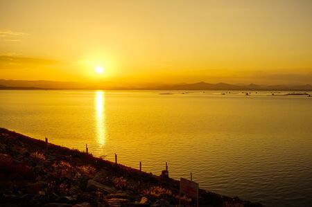 People are taking a rest on dam with sunsetの写真素材