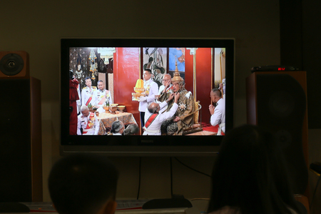 Bangkok, Thailand, May 4, 2019: A Thai girl watching the Royal Coronation via live TV at her home. His Majesty the King attends the Song Muratha Bhisek or Royal Purification ceremony.のeditorial素材